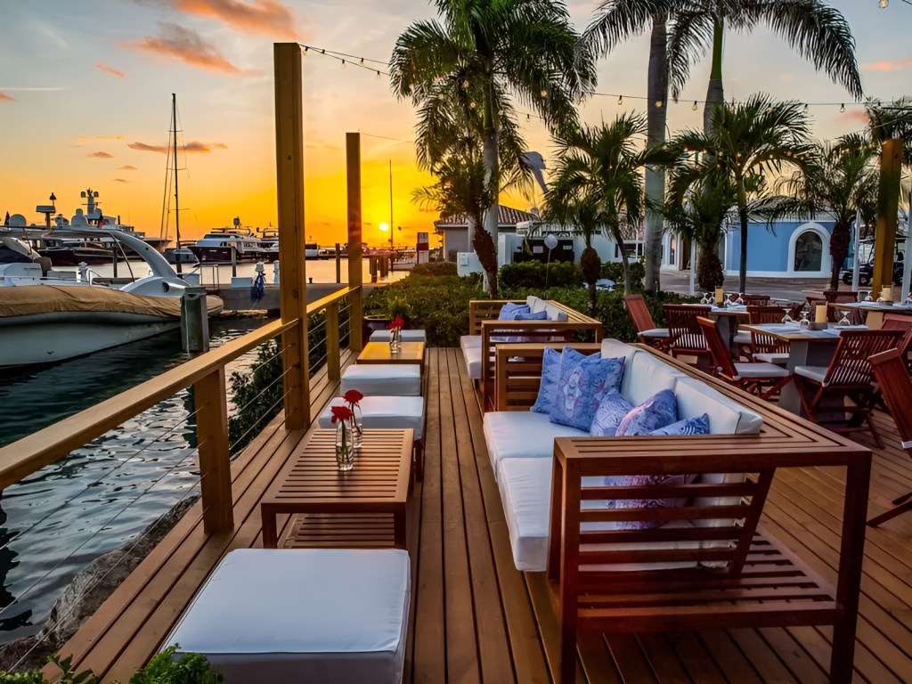 Zona de terraza del restaurante La Casita con vistas a los yates del puerto deportivo Casa de Campo al atardecer.